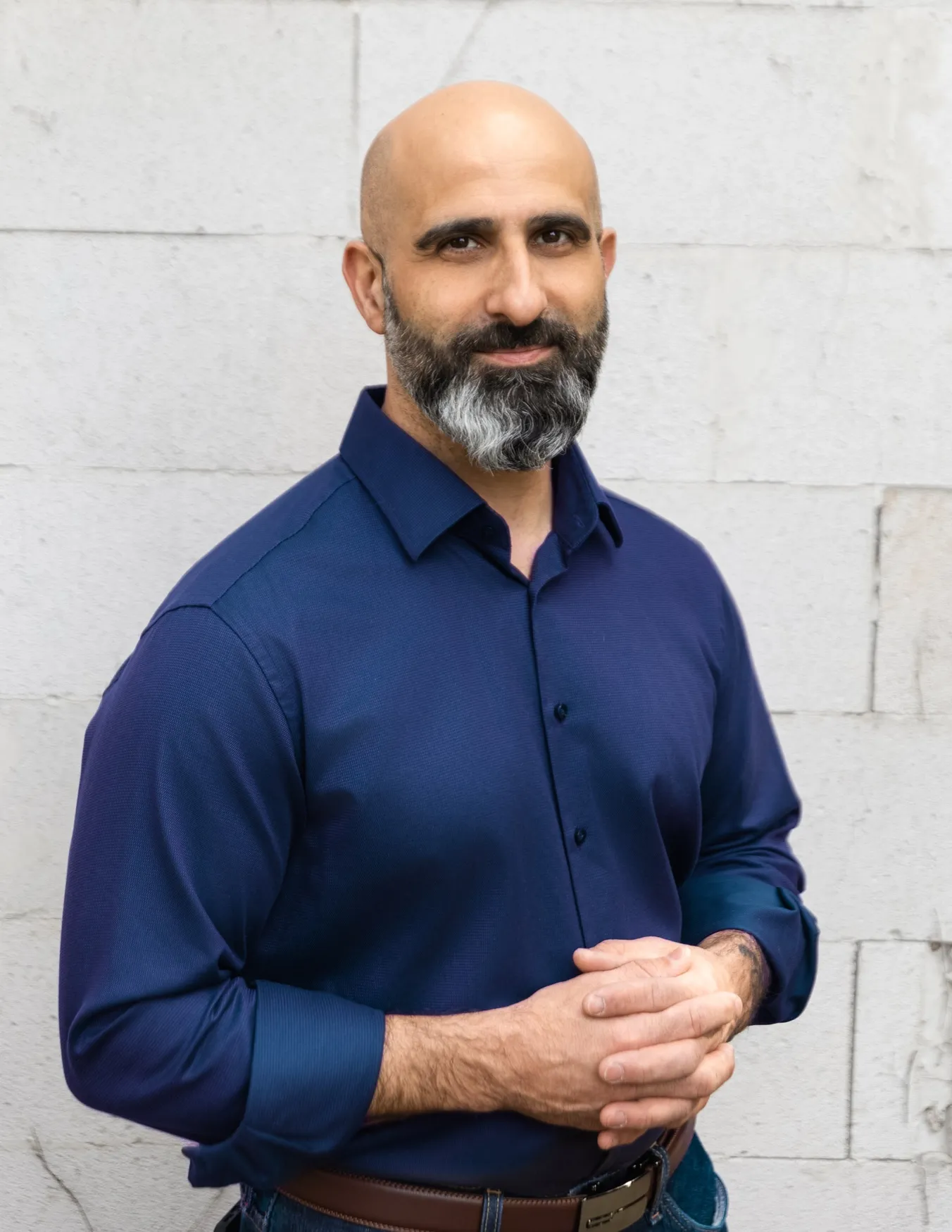 Nader Samadi Tehrani vor einer weiß gestrichenen Steinmauer, dunkelblaues Hemd mit hochgekrempelten Ärmeln, er blickt in die Kamera